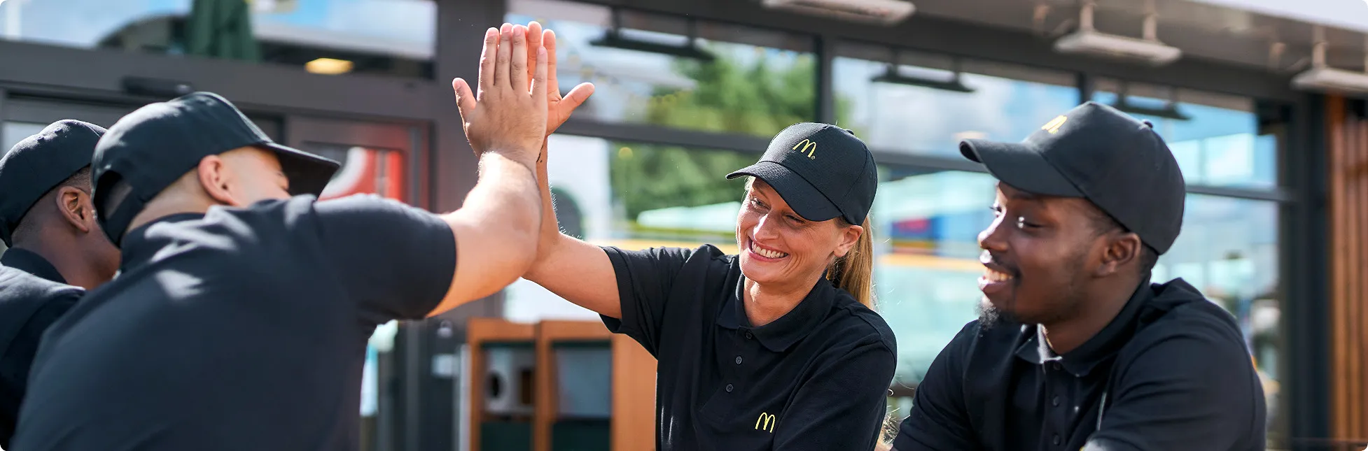 McDonald's crew members smiling and giving a high five outside the restaurant